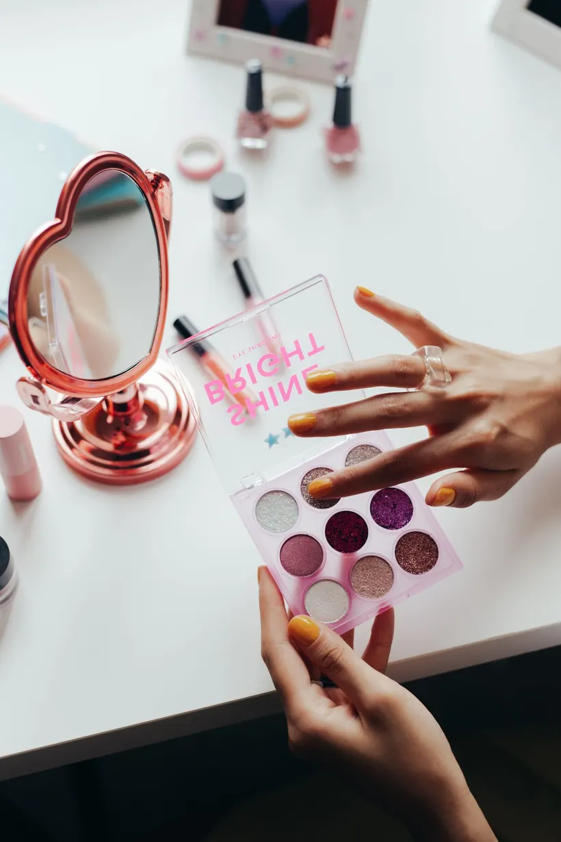 Manos con uñas cuidadas eligiendo tonos de maquillaje