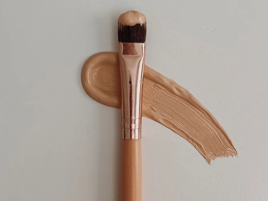 Brocha de maquillaje sobre base beige para calcular materiales de un curso online