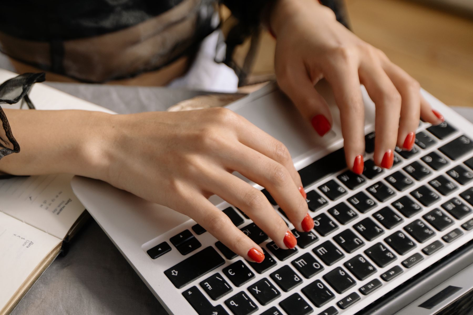 Manos con manicura tomando notas mientras se revisa información de un curso en un portátil