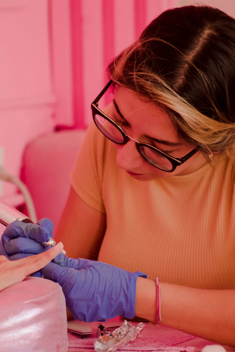 Manicurista trabajando con torno y guantes durante una práctica técnica