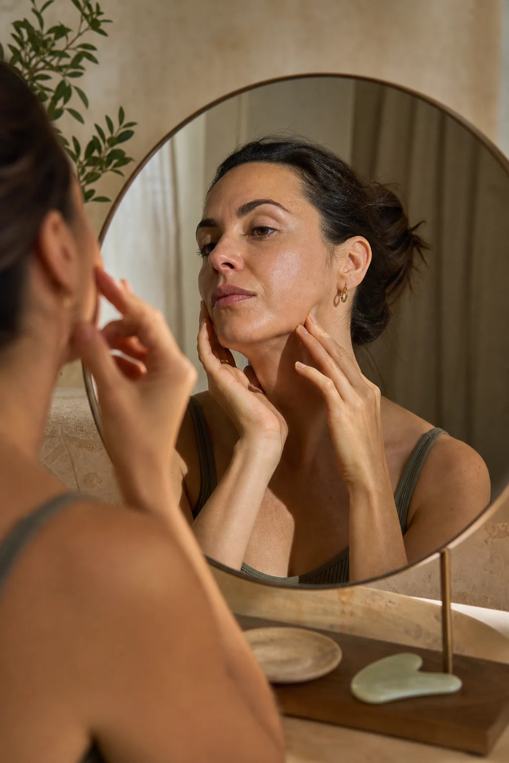 Mujer realizando un gesto de yoga facial frente a un espejo