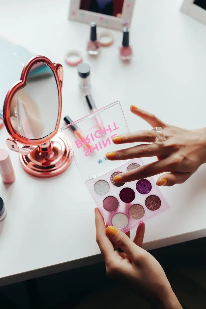 Manos con manicura cuidada seleccionando tonos de maquillaje